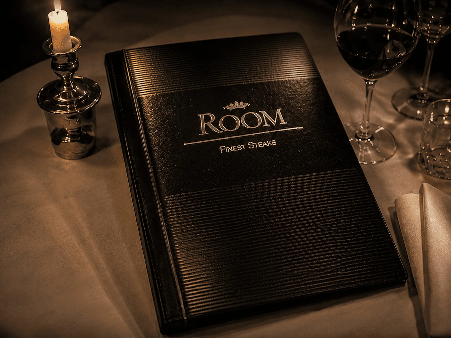 ROOM menu in a leather cover on a set table with a candle